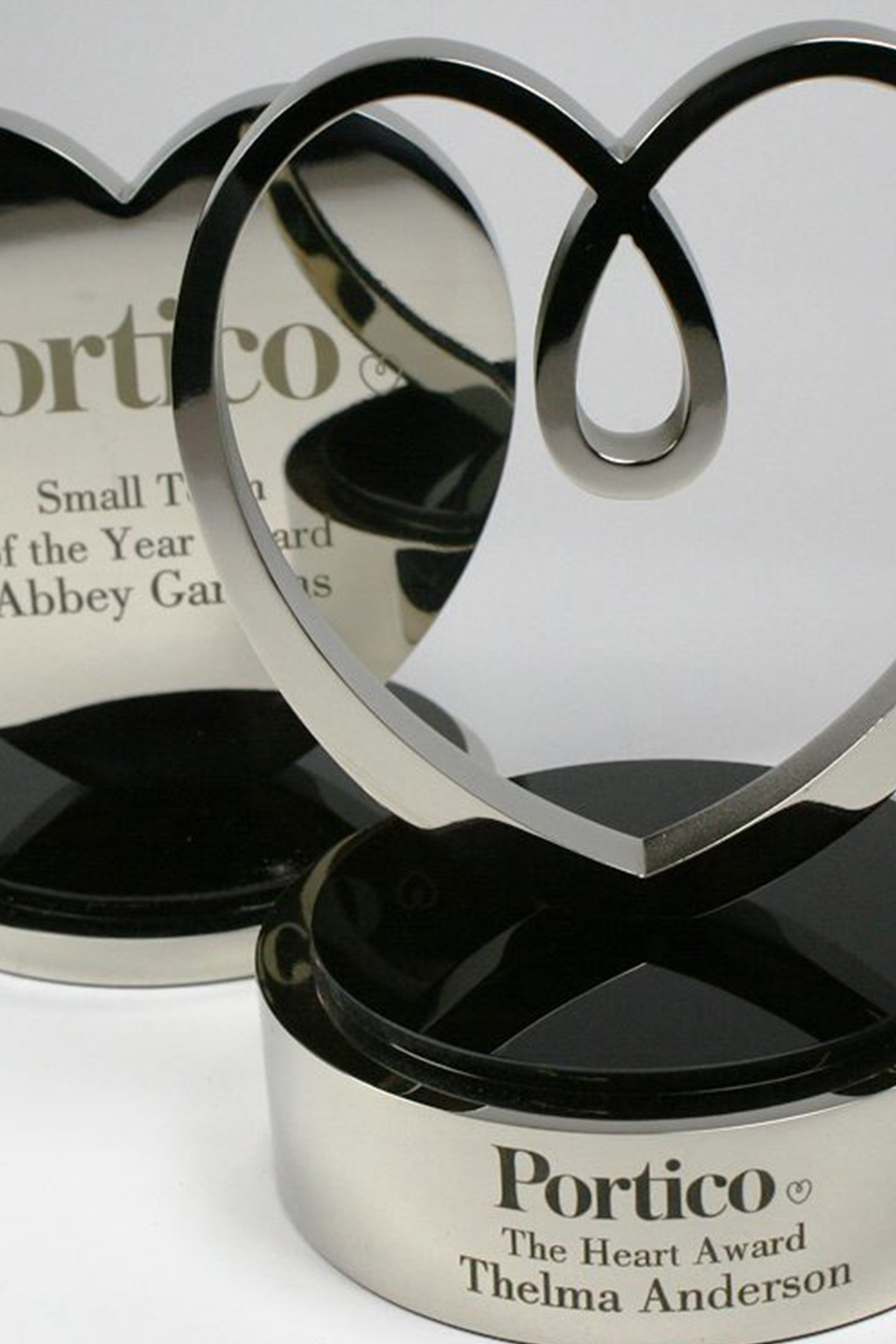 A champagne gold cup, a clear glass award and a circular gold trophy on burgundy plinths.